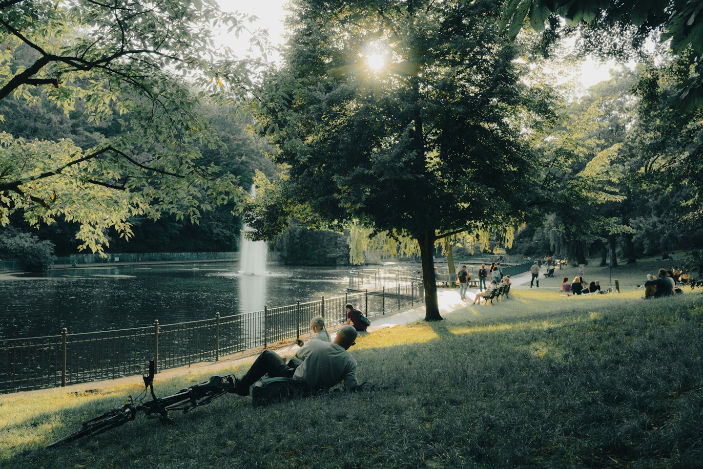 Couple se relaxant sur une colline herbeuse avec un vélo près de l'étang du parc.