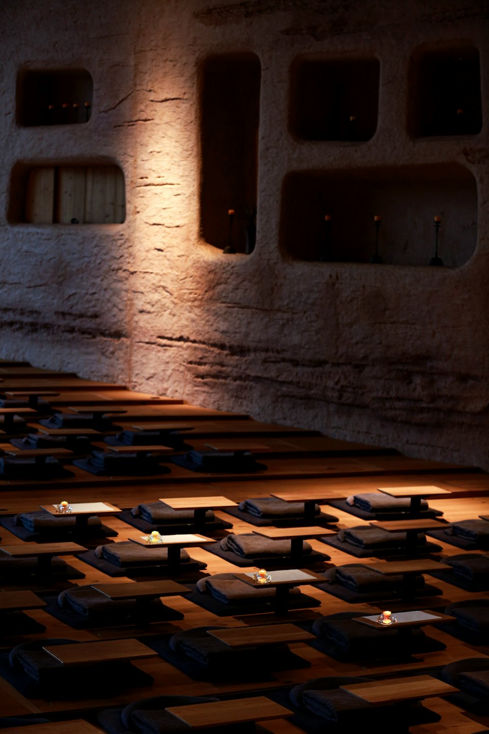 Salle de méditation vide avec coussins et bougies au sol.