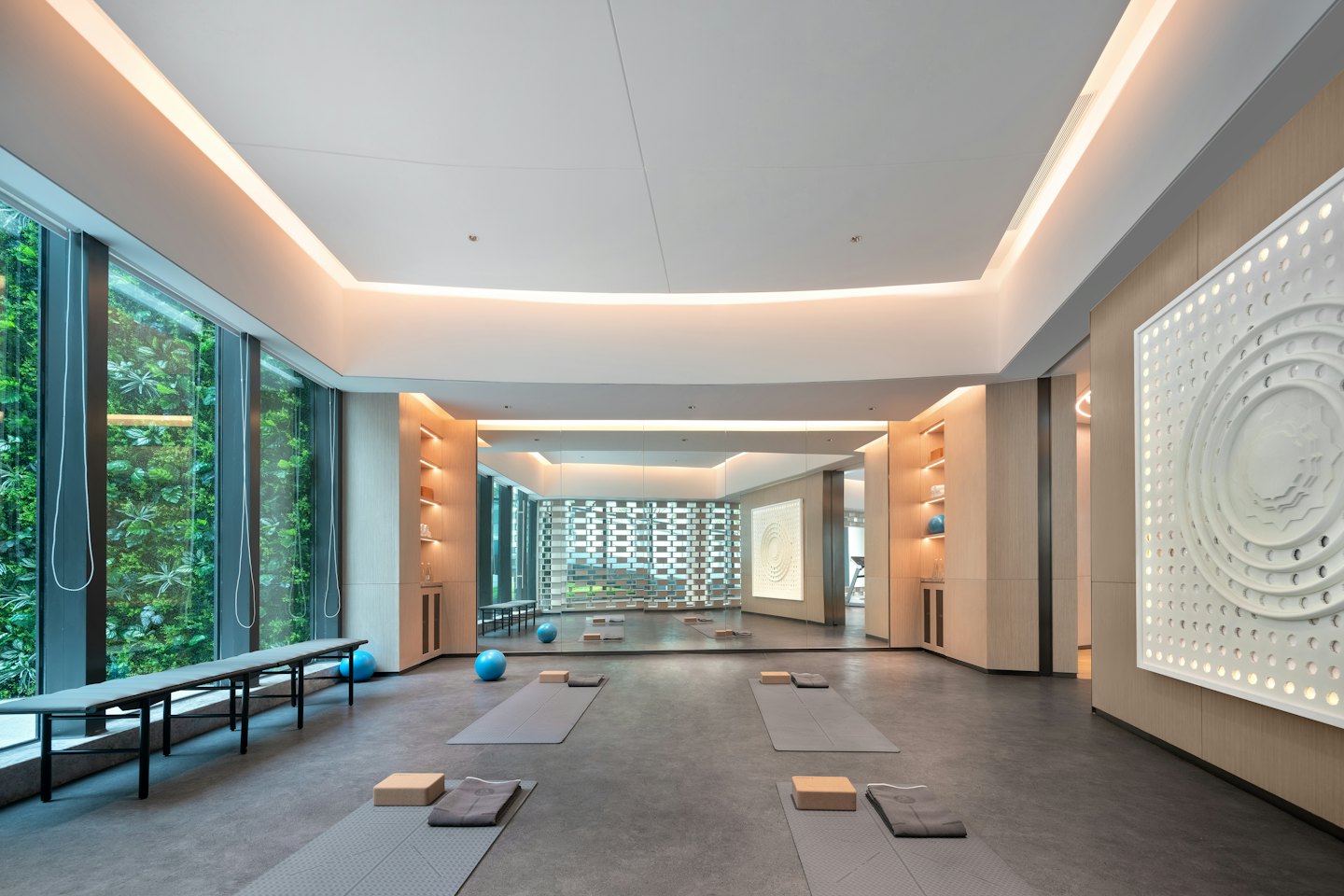 Tapis et blocs de yoga gris disposés dans un studio spacieux et ensoleillé.